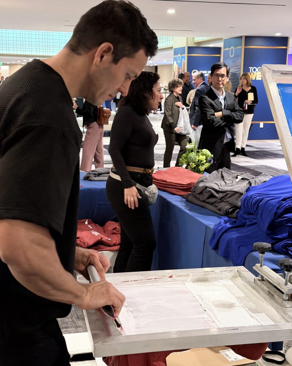 Operator peeling a printed DTF transfer film off a freshly pressed shirt at an event